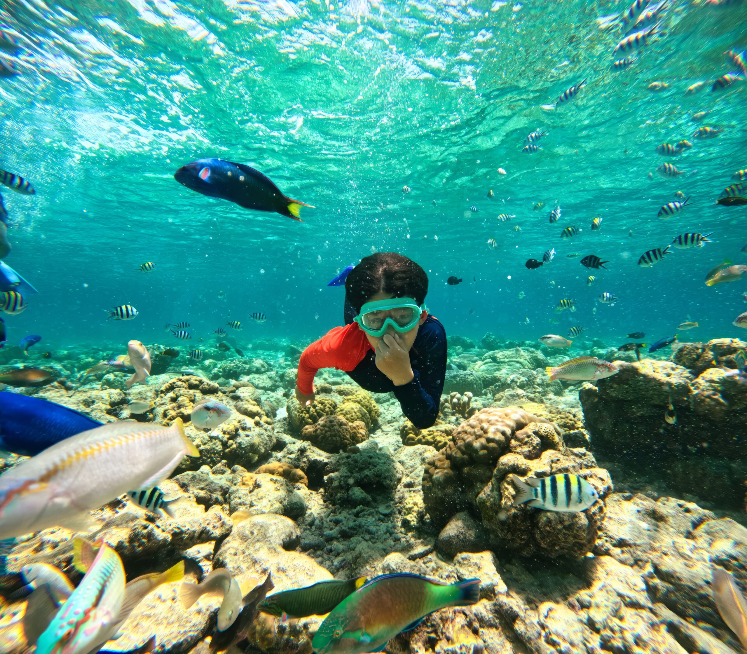 Young boy in a wetsuit and goggles swimming in the water